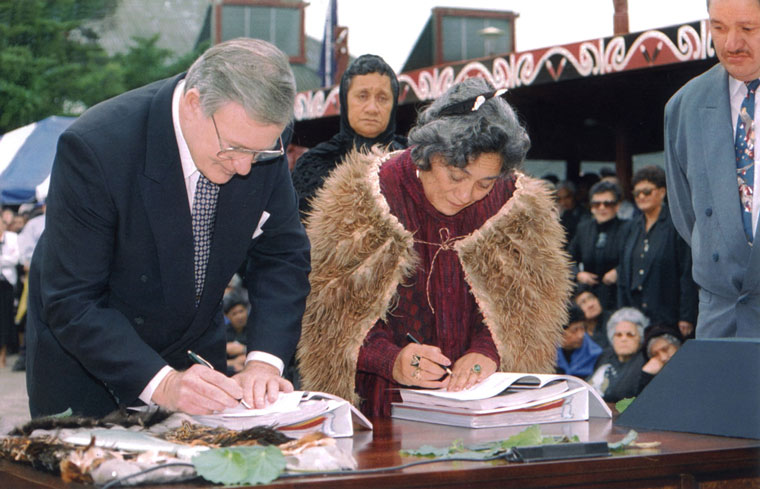 Jim Bolger and Dame Te Atairangikaahu signing a document.
